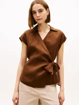 Blusa cruzada sin mangas de lino color marrón, con cuello en V, cuello inglés y lazo anudable en el lateral.