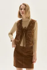 Falda corta de cuero color marrón, con diseño de flecos largos desmontables que cubren toda la prenda. Presenta un estilo western con cierre en la cintura.