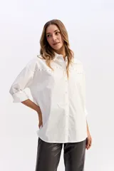 Camisa de algodón color blanco, de corte relajado y estilo western. Presenta detalle de tachas metálicas en la parte superior delantera y mangas largas con puños.