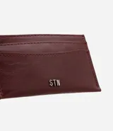 Billetera compacta de poliuretano color bordó, de diseño slim con compartimentos para tarjetas y aplicación metálica frontal con el logo de la marca Satinato.