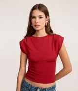 Top ajustado color rojo, con cuello redondo y mangas cortas tipo hombreras o almohadillas. El tejido parece ser de punto o viscosa con buena caída y presenta un fruncido horizontal a la altura de la cintura.