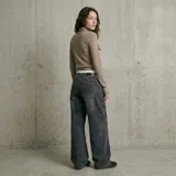 Polera negra de manga larga con cuello alto y detalle de lazo lateral en el cuello.