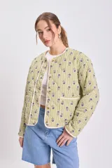 Cazadora capitoneada de corte recto, con diseño de rayas verticales verdes y estampado floral. Presenta cuello redondo, cierre frontal con botones y bolsillos laterales de parche.