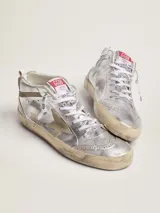 Zapatilla de caña media inspirada en el estilo skate de los ochenta, confeccionada en cuero vacuno plateado con efecto envejecido, estrella lateral y detalles en gamuza beige. Incorpora perforaciones de estilo inglés, cordones blancos con logotipo y suela de goma con acabado desgastado.