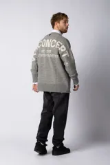 Sweater oversize de tejido de punto en color gris, con cuello redondo, puños y ruedo acanalados con detalles de desgaste. Presenta un diseño minimalista con logo tejido en la espalda.