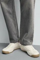 Zapatilla de cordones estilo retro, color negro con detalles en blanco y suela de goma color caramelo.