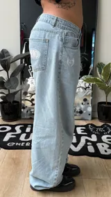 Pantalón de jean estilo baggy, color celeste claro, de tiro alto y corte amplio con detalles bordados en los bolsillos.