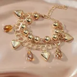 Pulsera dorada de múltiples cadenas con dijes de corazones y cristales color ámbar.