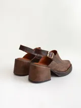 Zapato tipo zueco de cuero color chocolate con efecto desgastado, plataforma y taco cuadrado. Presenta una tira trasera ajustable con hebilla metálica.