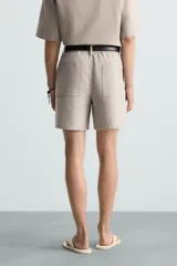 Bermuda de algodón color blanco, de corte relajado, con cintura elástica, bolsillos frontales y bolsillos traseros de plastrón. Cierre frontal con cremallera y botón.