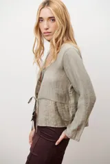 Chaqueta ligera de manga larga en color azul, con escote en V y cierre frontal mediante dos lazos ajustables. Presenta un diseño fluido con textura sutil y corte recto.