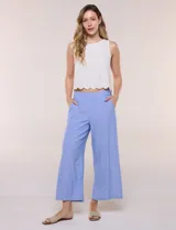 Pantalón crop de lino y rayón, con diseño wide leg de corte holgado, estampado tropical de hojas en tonos verde, azul y marrón sobre fondo blanco. Cuenta con pretina trasera elastizada y bolsillos delanteros.