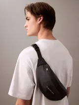 Riñonera negra de poliéster reciclado con logo Calvin Klein Jeans estampado en gris en el frente. Tiene correa ajustable con clip.