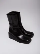 Bota de caña media en color negro con textura efecto cocodrilo y taco cuña.