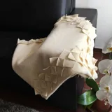 Manta de lana afieltrada color crema, con terminaciones decorativas de figuras geométricas.