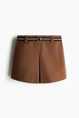 Short pollera mini de sarga color marrón, con pliegue frontal y cierre lateral oculto. Incluye un cinturón elástico a rayas con hebilla metálica redonda.