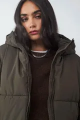 Campera puffer color verde militar, acolchada, con capucha y cierre frontal de cremallera.