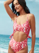Traje de baño enterizo con estampado de ondas en tonos rosados y blancos, con abertura en el abdomen y lazos ajustables en los laterales.
