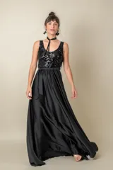 Vestido largo rojo con cuerpo de lentejuelas y falda de satén con caída fluida. Presenta escote redondo, sin mangas y un lazo en la cintura.