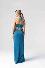 Vestido largo de fiesta color petróleo, con escote halter con detalle de cuentas, aberturas laterales en la cintura y tajo en la pierna.