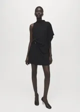 Vestido corto negro de poliéster con diseño asimétrico, un hombro descubierto, manga murciélago en el otro lado y detalle drapeado en la cintura con broches metálicos.