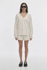 Short tipo bóxer de felpa sin frisa, color crudo con estampado de lunares negros. Cuenta con cintura ajustable y calce holgado.