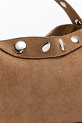 Cartera tipo bandolera de gamuza color marrón, con correa ajustable mediante hebilla y cierre superior.