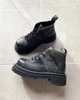 Botas acordonadas de cuero vacuno con efecto desgastado, de caña media y suela track robusta. Presentan costuras a la vista en tono contrastante y tirador en la parte trasera.