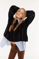 Sweater de punto negro con diseño de rayas verticales en relieve y costuras decorativas en color marrón, de corte holgado y manga larga.