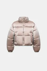 Anorak acolchado de efecto brillante con tejido cortavientos y repelente al agua. Presenta cuello subido, cierre frontal con cremallera, bolsillos delanteros con forro polar y cierre de cremallera, y mangas largas con puños elásticos. El bajo es ajustable con cordones elásticos laterales.