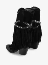 Bota de caña media de gamuza color negro, con taco medio ancho y punta ligeramente cuadrada. Presenta un detalle de flecos en capas que cubren la parte inferior de la caña y una tira de cuero con tachas metálicas plateadas rodeando el tobillo.