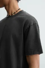 Camiseta de corte boxy fit, con cuello redondo y manga corta. Presenta un acabado irregular con efecto lavado que le otorga un aspecto vintage.