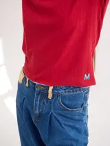 Polera de cuello alto confeccionada en tela rib color blanco, con mangas largas y hombreras. Presenta pespuntes en contraste en las terminaciones del cuello, hombros y puños.