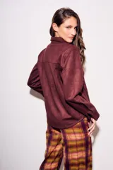 Camisa color marrón de gamuza sintética, de corte recto, con cuello clásico, cierre frontal con botones y mangas largas.