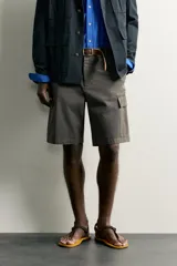 Bermuda cargo color verde militar de corte relaxed fit, confeccionada en tejido de algodón. Cuenta con bolsillos laterales con solapa en las perneras, trabillas en la cintura con ajuste lateral y cierre frontal con cremallera y botón.