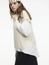 Chaleco de punto gris con escote en v y textura metalizada. Presenta mini tajos verticales en los laterales.