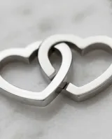 Collar de acero con cadena fina y dije compuesto por dos corazones entrelazados.