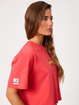 Remera coral cropped, de manga corta, con estampa trasera colorida de un perro surfeando y el texto "Rusty County Surf Club".