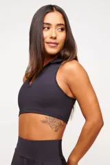 Top deportivo negro, estilo crop top, con cuello polo y escote en V. Presenta tirantes anchos y corte ajustado al cuerpo.