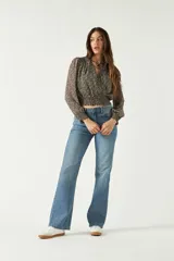 Blusa de manga larga con estampado floral pequeño sobre fondo oscuro. Presenta escote en V con lazo para anudar, cintura con frunce elástico y puños ajustados.