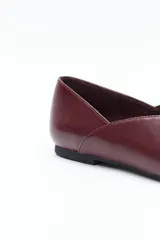 Zapato bajo de mujer, color negro, con punta fina y escote pronunciado en forma de V en el empeine. Presenta un acabado liso y una suela baja y plana.