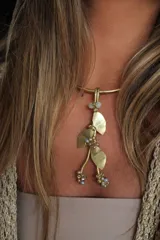 Gargantilla rígida dorada con dije colgante de hojas y cuentas de colores.