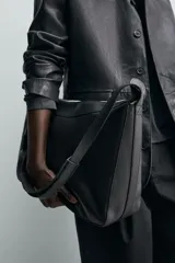 Bolso de hombro de diseño minimalista confeccionado en piel de alta calidad. Cuenta con un compartimento principal con cierre de cremallera, interior con bolsillos organizadores y asa de hombro fija. Incluye un detalle de llavero colgante.