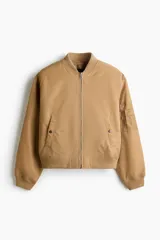Campera bomber de nylon color tostado, con cuello, puños y bajo acanalados. Presenta cierre frontal, bolsillos laterales con botón a presión y un bolsillo con cierre en la manga.