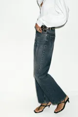 Jeans de tiro alto con diseño de cinco bolsillos y corte recto que se estrecha hacia el tobillo. Incluye un cinturón negro con tachas metálicas. Cierre frontal con cremallera y botón.