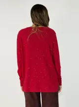 Sweater de punto color beige con sutiles destellos brillantes, cuello redondo, manga larga con puños acanalados y diseño asimétrico con el ruedo trasero más largo que el delantero.