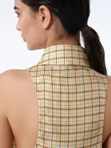 Camisa sin mangas con cuello italiano y cierre con botones visibles.