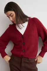 Cardigan de punto acanalado color bordó, con escote en V, cierre frontal de botones y mangas largas abullonadas con puños ajustados.