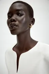 Camiseta negra de cuello redondo con escote en pico, manga corta abullonada y bajo con diseño peplum.