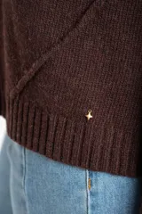 Sweater de tejido de punto liso, color marrón oscuro, con cuello redondo y calce oversize. Presenta detalles de costura en diagonal en la parte inferior delantera.